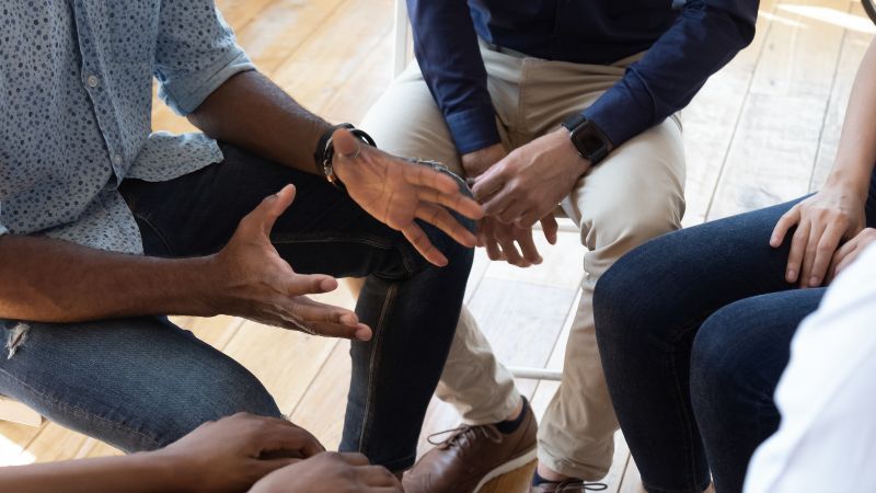 Bildauschnitt der Hände einer sitzenden Personengruppe