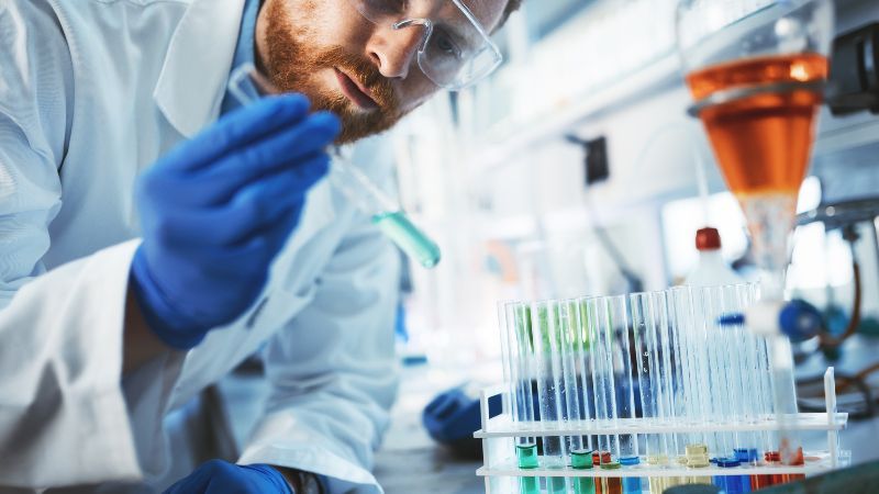 Mann mit Reagenzröhrchen in der Hand im Labor