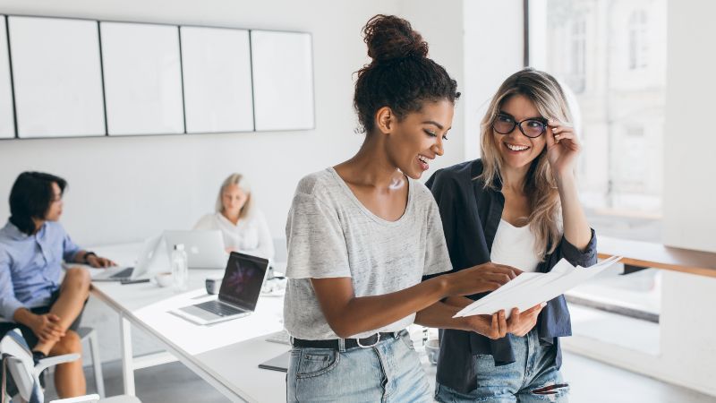 Zwei Frauen im Vordergrund stehend - zwei Frauen im Hintergrund sitzend