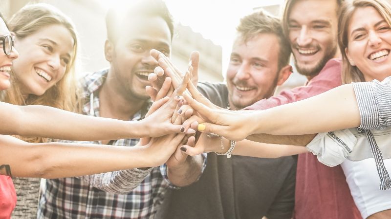 Junge glückliche Menschen führen in ihrer Mitte Hände zusammen