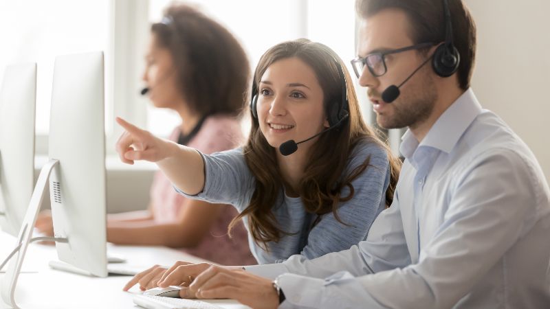 Frau und Mann mit Headsets vor Bildschirm