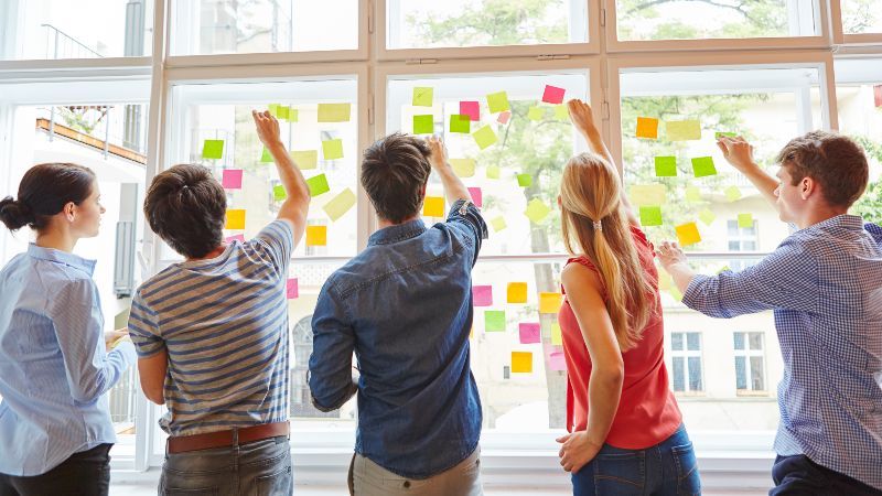 Fünf Personen vor Fenster mit Post-its