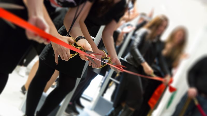 Rotes Band wird mit Schere zerschnitten