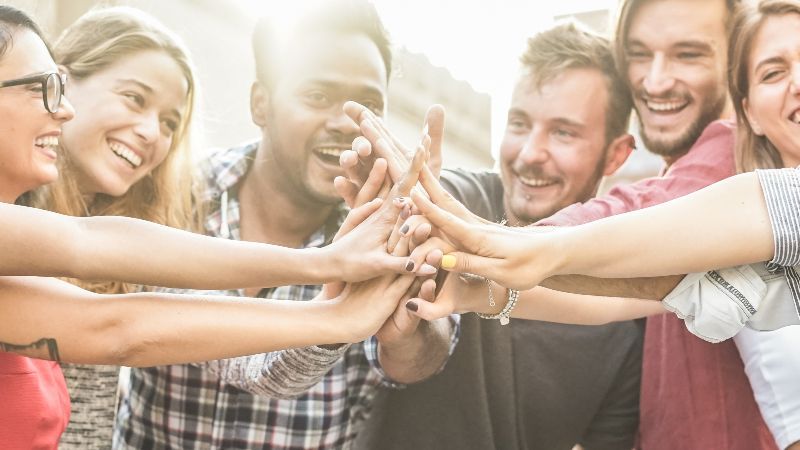 Fröhliche Menschen führen Hände zusammen