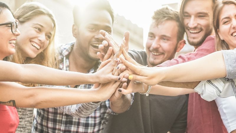 Fröhliche Menschen führen Hände zusammen