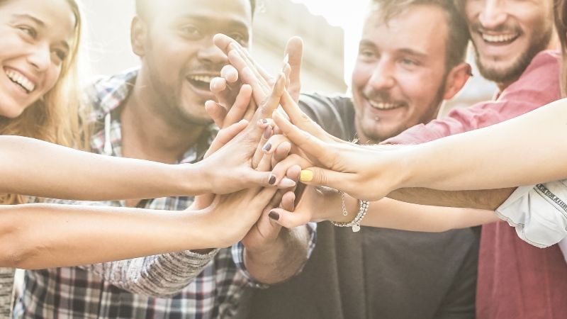 Fröhliche Menschen führen Hände zusammen