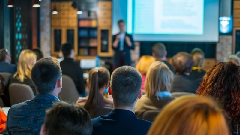 Sitzendes Publikum vor stehendem Vortragenden