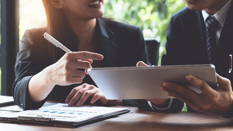 Frau mit Schreibstift und Mann mit Tabletcomputer im Gespräch