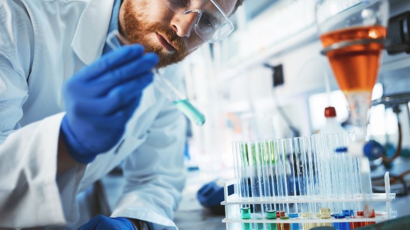 Mann mit Reagenzröhrchen in der Hand im Labor