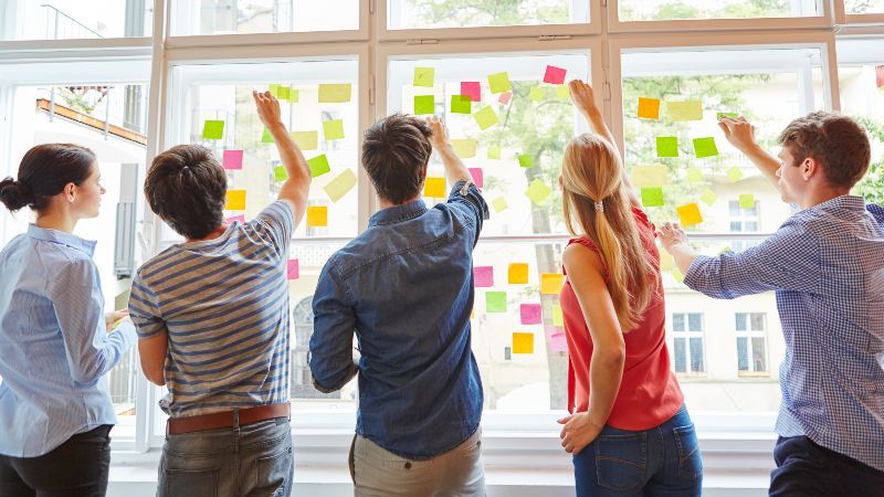 StudentInnen kleben Post-its an ein Fenster