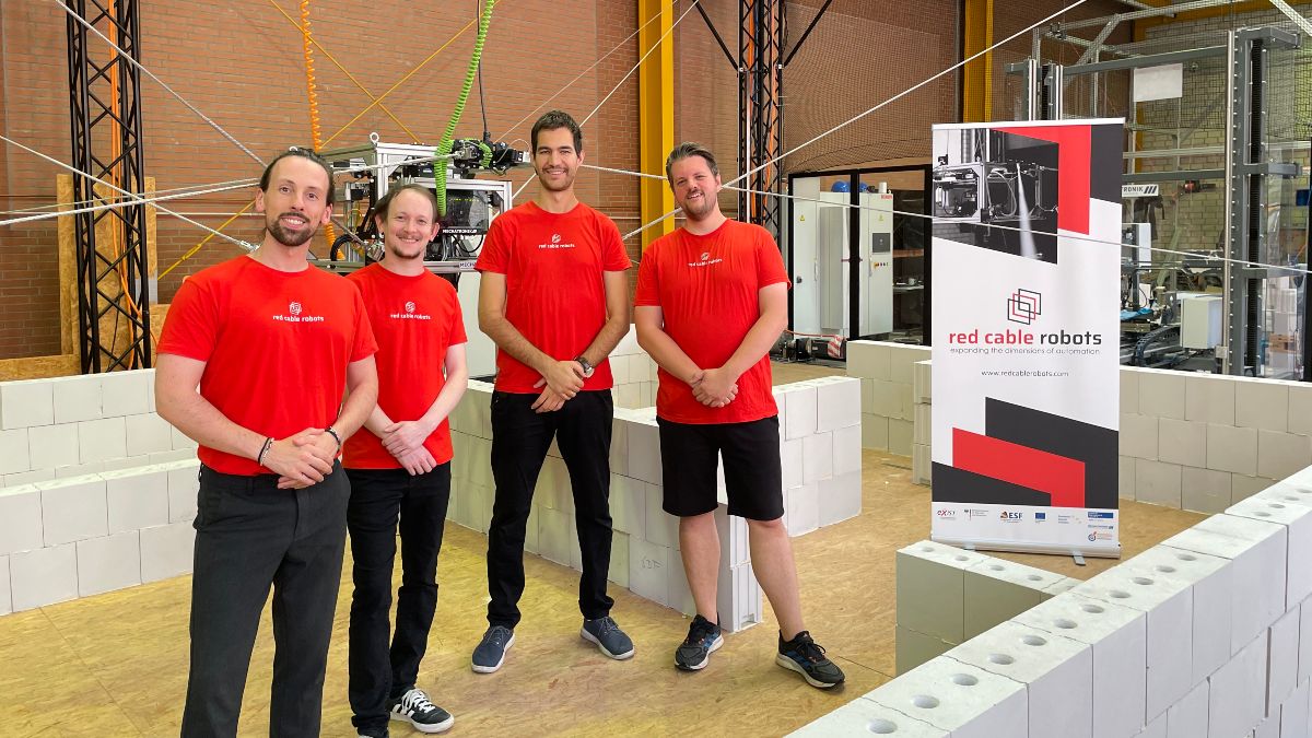 Vier junge Männer in roten T-Shirts in einer Werkhalle