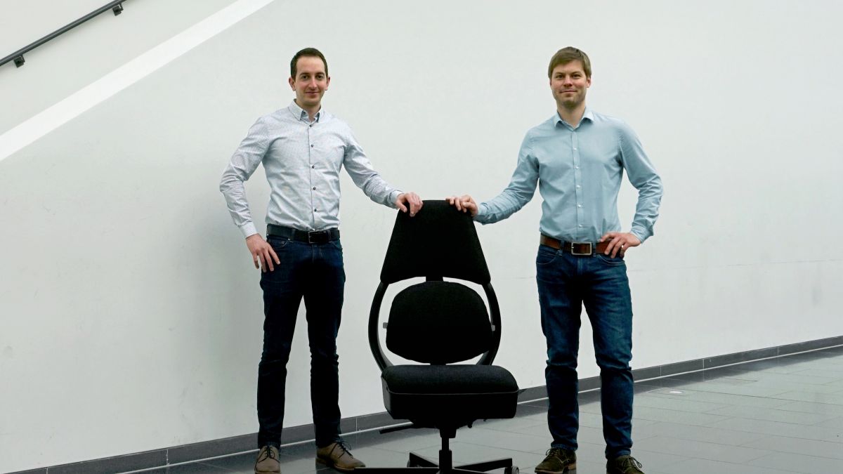 Zwei Männer rechts und links von einem Bürostuhl