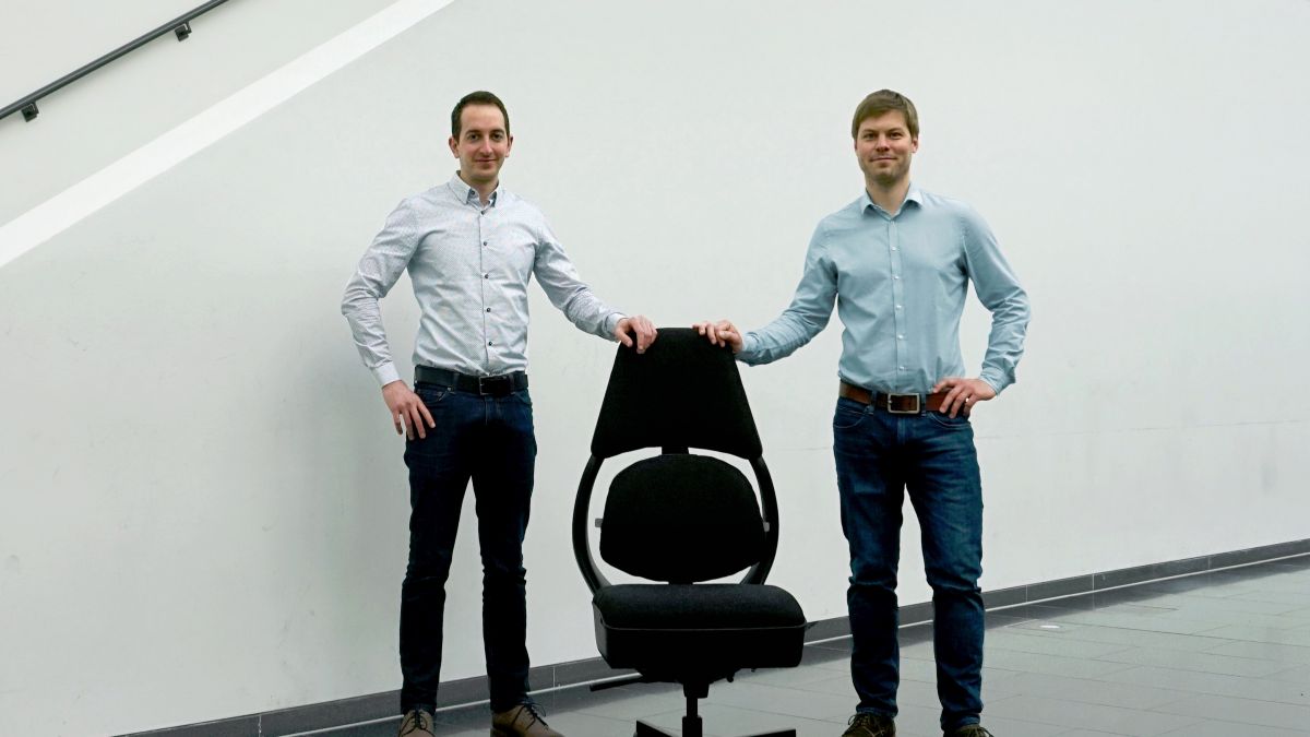 Zwei Männer rechts und links von einem Bürostuhl